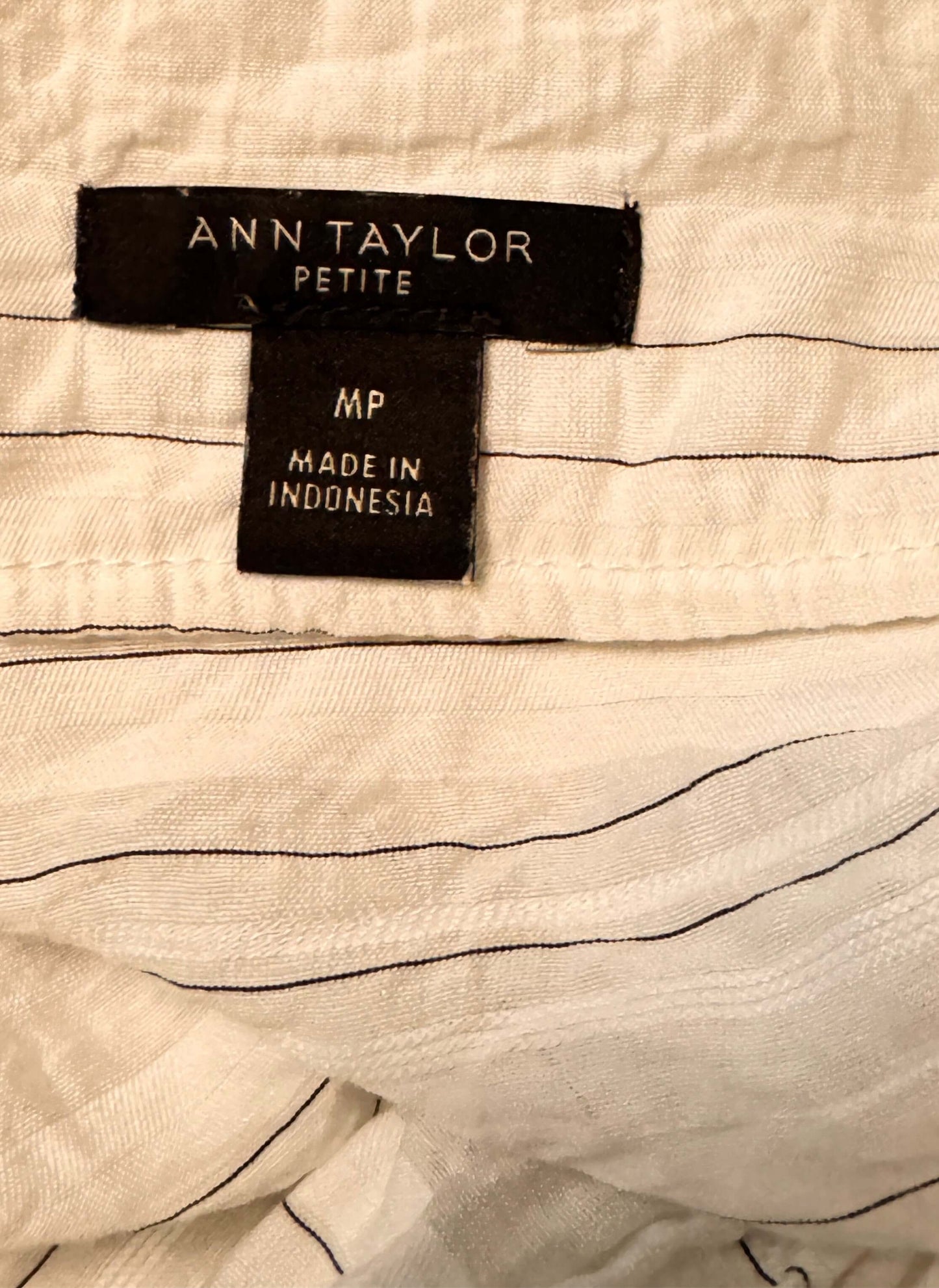 Close-up of Ann Taylor Petite label on a garment with black text.
