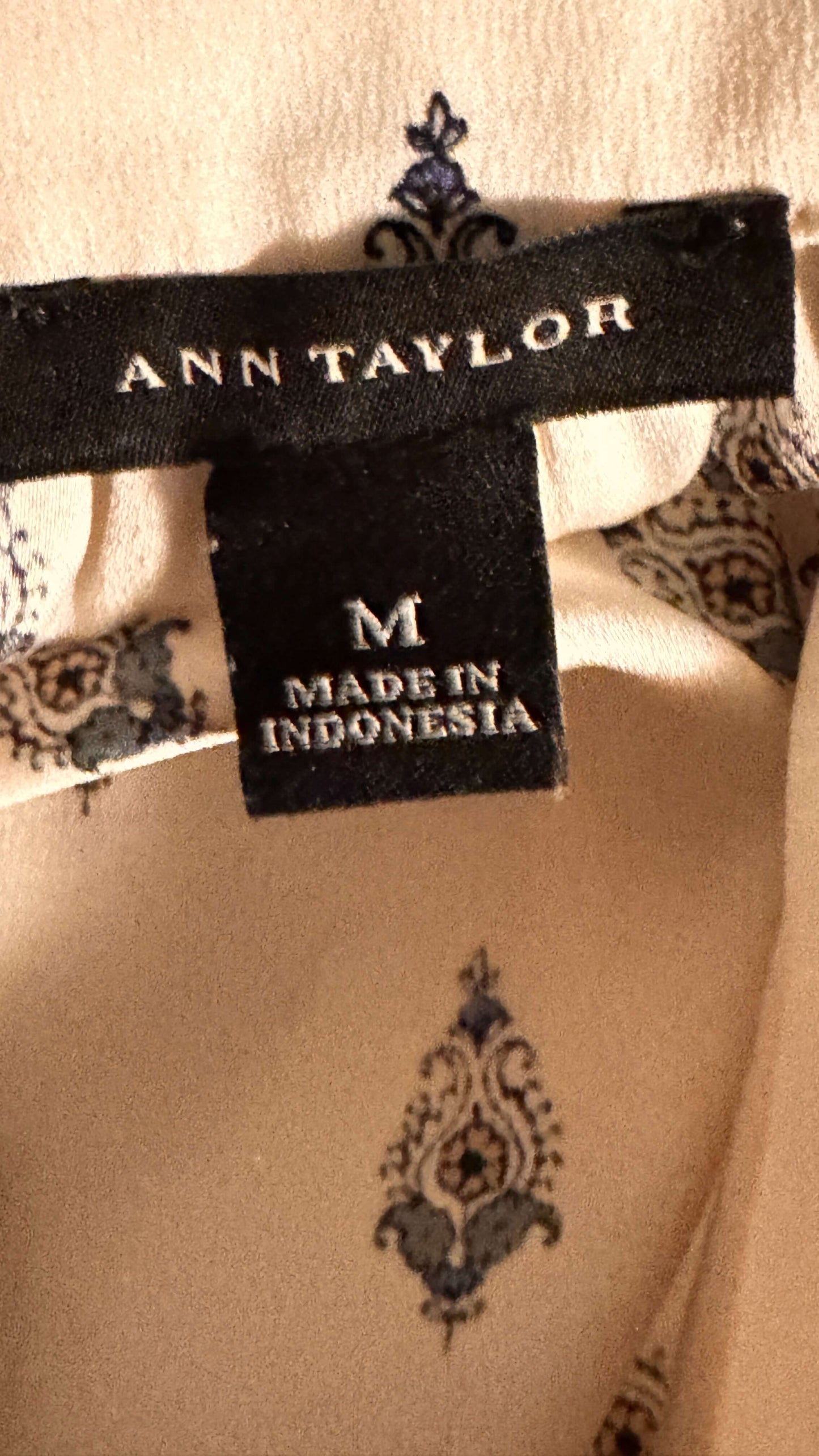 Close-up of Ann Taylor label showing medium size in elegant patterned blouse.