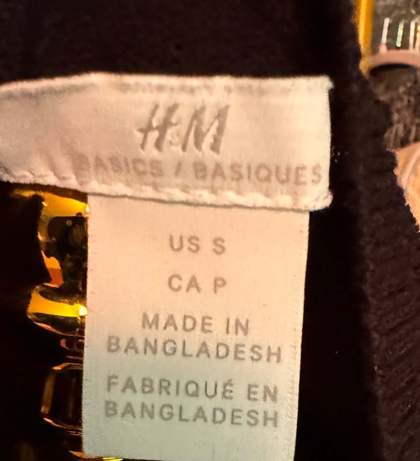 Close-up of an H&M label on a garment with text indicating size, country of manufacture, and fabric origin.