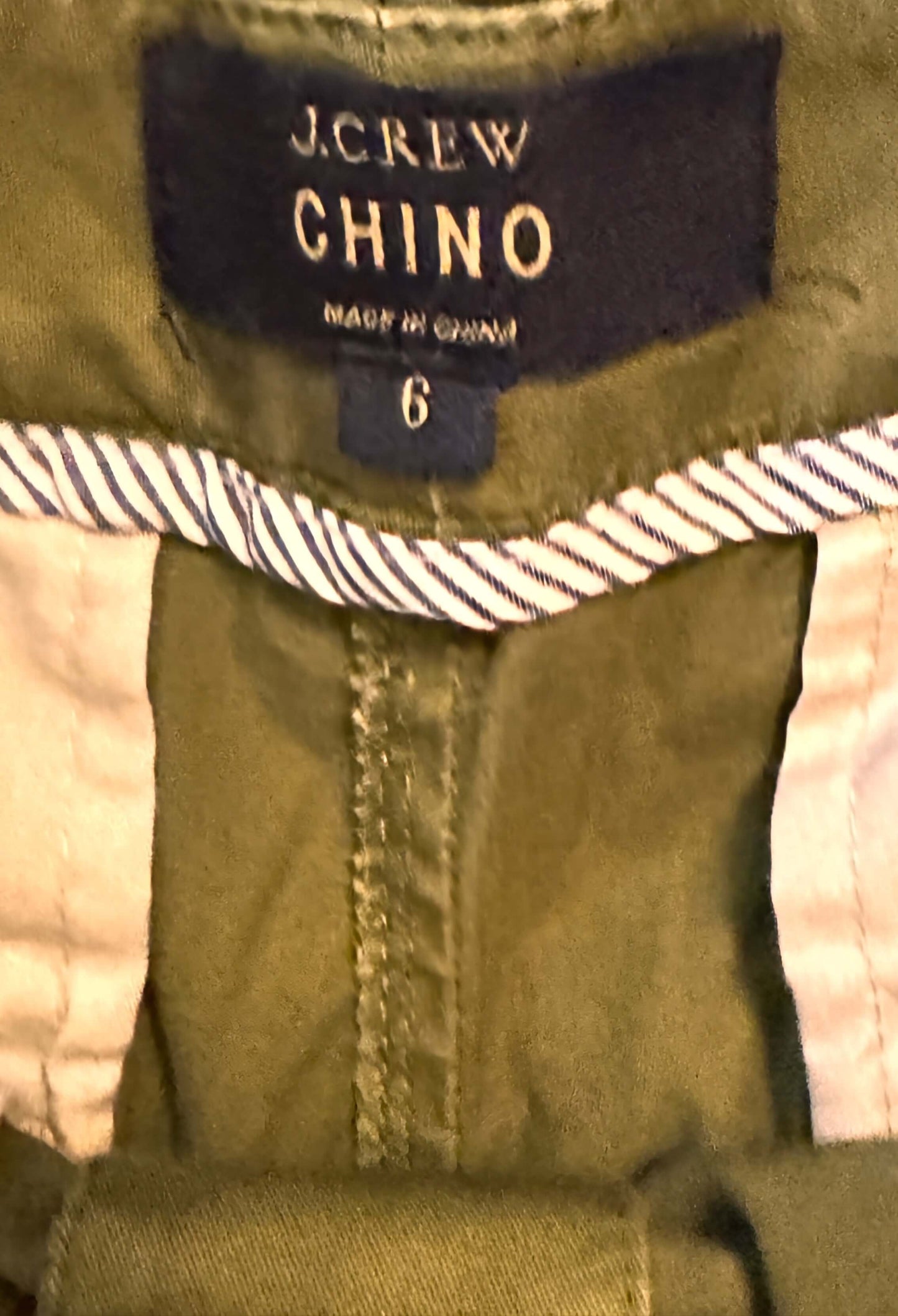 Close-up of J.Crew Chino label on a green fabric with pink lining.