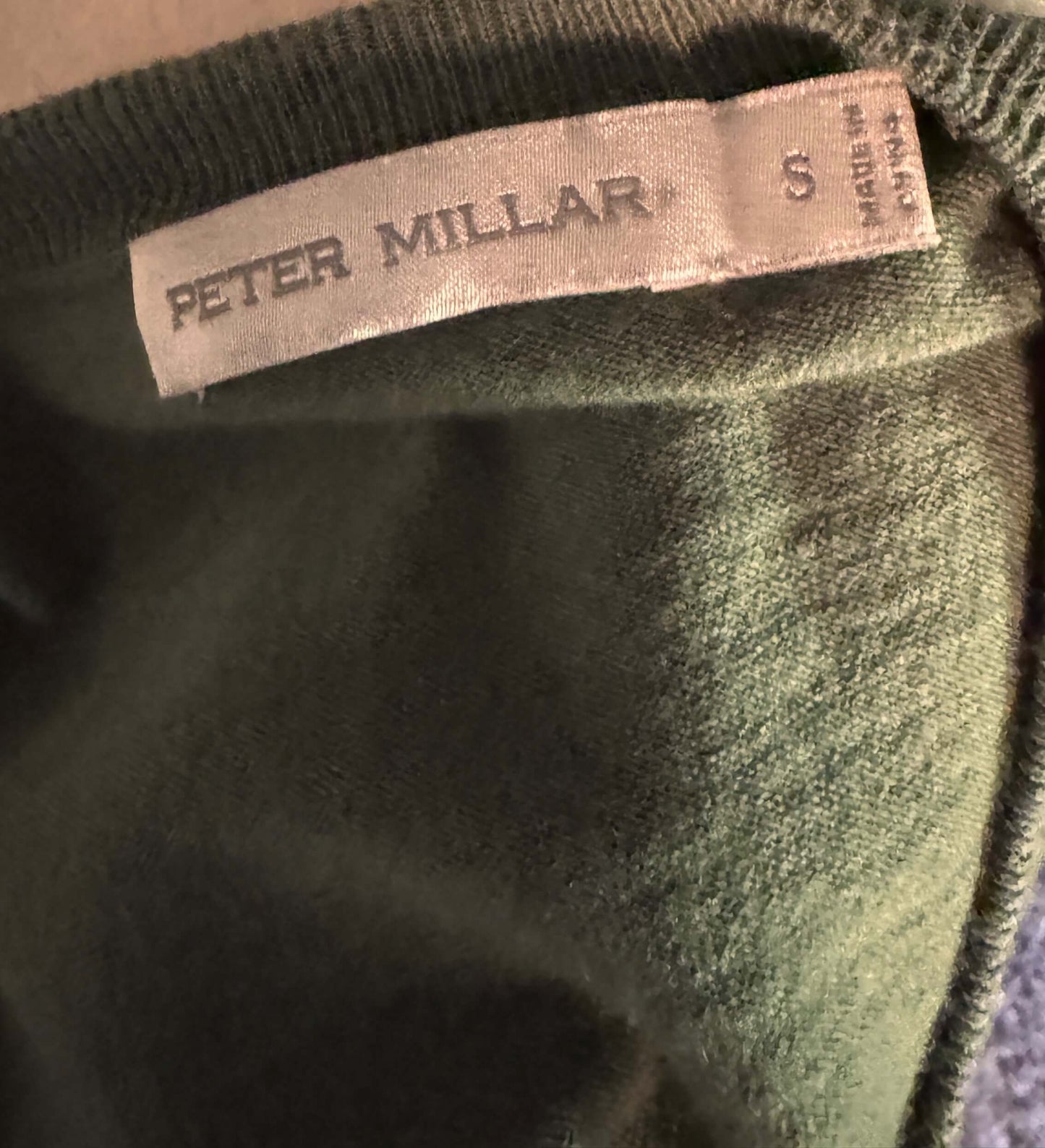 Green fabric with a 'Peter Millar' label on a brown background