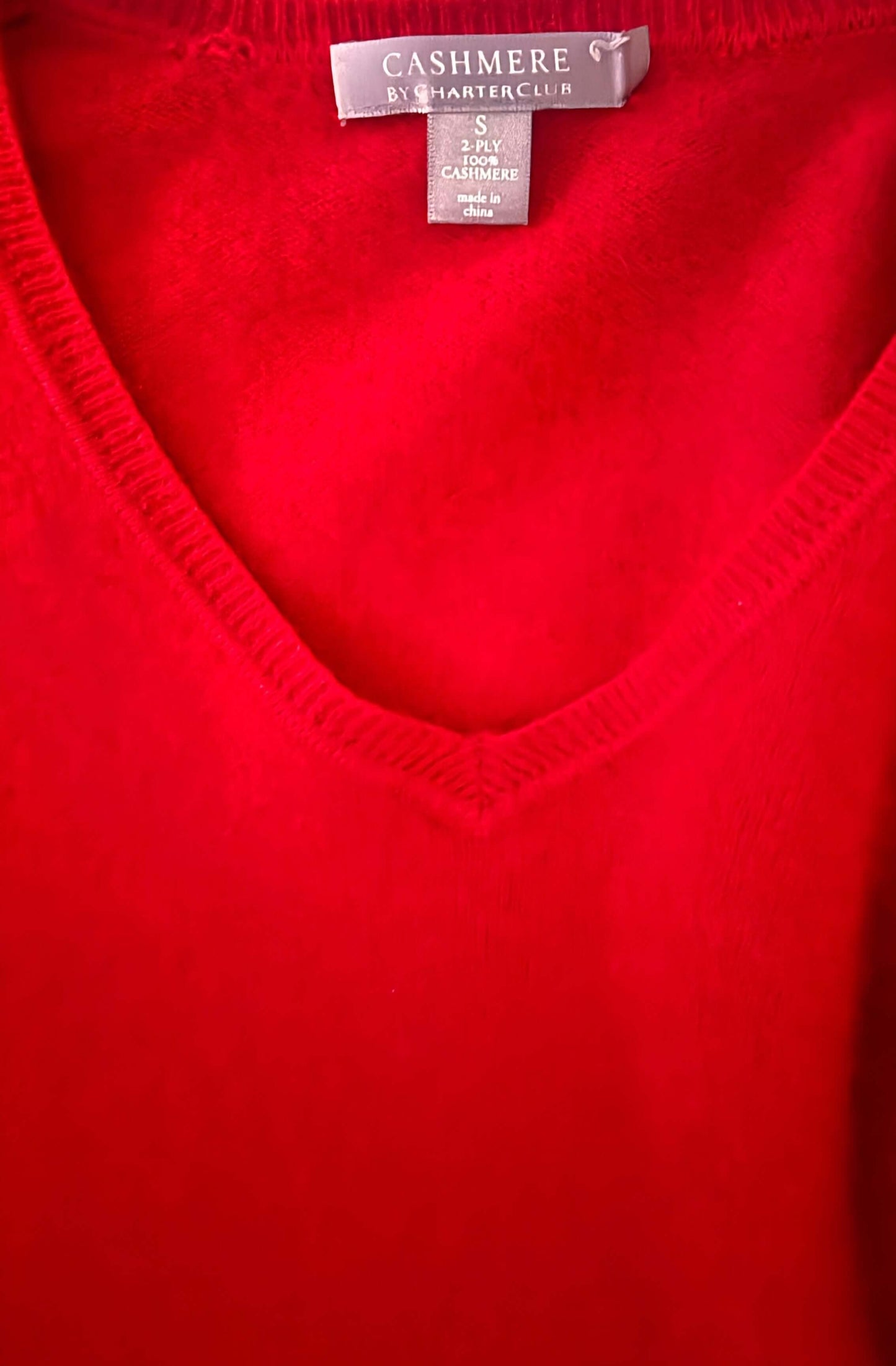 Red cashmere sweater with a brand tag on a white background