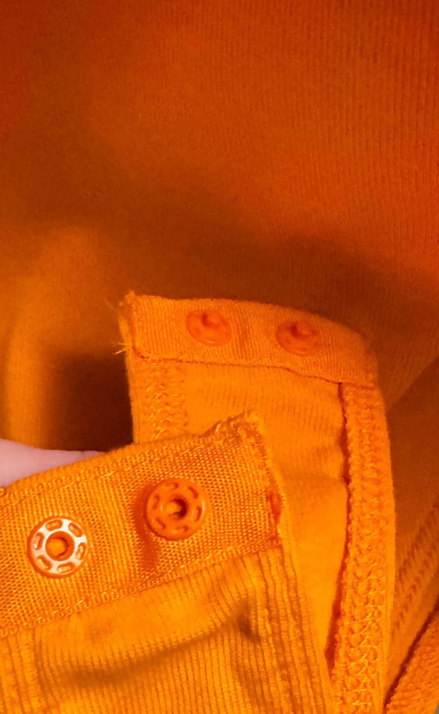 Close-up of orange buttons and fabric detail on Zara one-piece romper, showcasing stylish design.