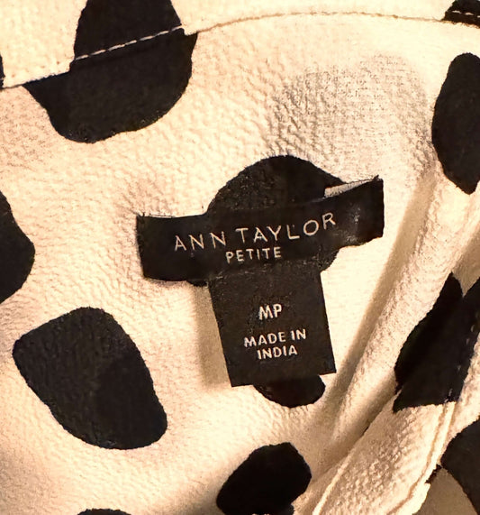 Close-up of a black Ann Taylor label on a garment with a polka dot pattern.