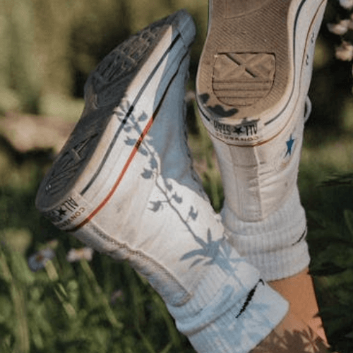 Pre-worn Chuck Taylor Converse All Star High-tops in size 7 with shadow on grass background.