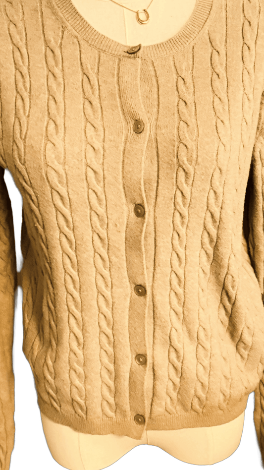Beige cable knit cardigan on a mannequin with a plain background